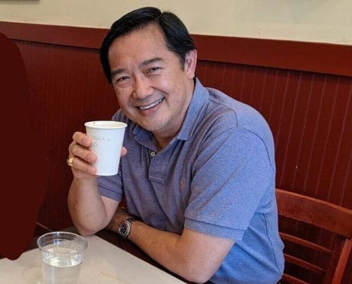 A man sitting at a table with a cup of coffee.