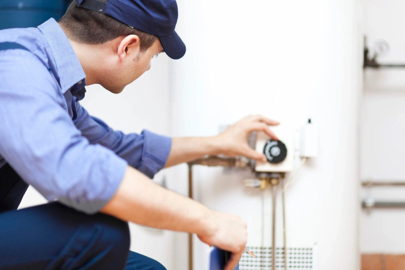 A man in blue shirt fixing a water heater.